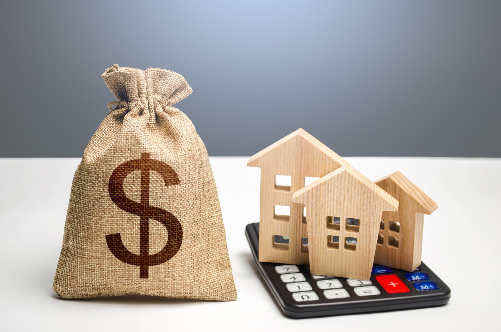 Houses on a calculator and dollar money bag.